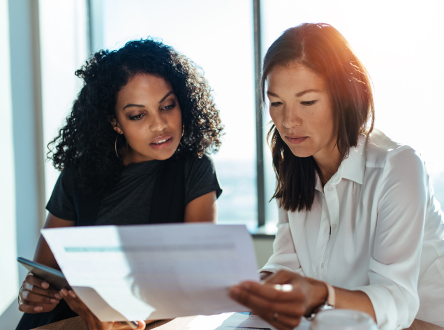 two woman reviewing a spreadsheet